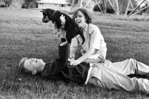 amoyed: Anthony Michael Hall and Molly Ringwald playing with a puppy during a break in location shoo