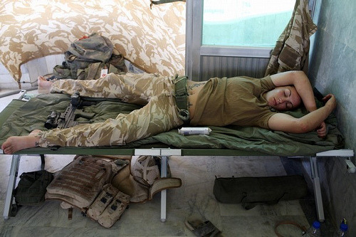  Nap time… A tired female British soldier asleep on her cot, her SA80 rifle at her feet. Nice ink from what can be seen.   Some of the best sleep I’ve ever had looked like this