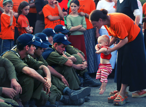 Trying to shame Israeli troops, a woman holds up her baby in front of the soldiers who were waiting 