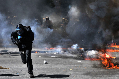 Athens, Greece: A protester runs from riot police during a general strike. Greece&rsquo;s two main t