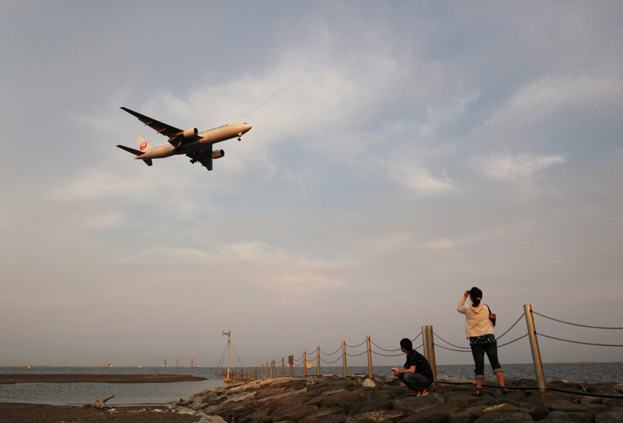 bloombergphotos:  A couple look at a Japan Airlines aircraft as it approaches to