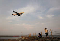 bloombergphotos:  A couple look at a Japan Airlines aircraft as it approaches to land at Haneda Airport at dusk in Tokyo, on Sept. 5. Photograph by Tomohiro Ohsumi/Bloomberg     