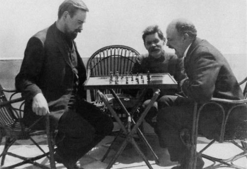 Lenin plays chess with Alexander Bogdanov. Maxim Gorky watches.