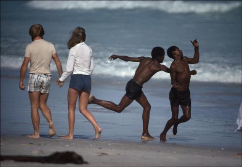 howtobeterrell:dynamicafrica: Two South African men amuse themselves on a legally white-only beach i