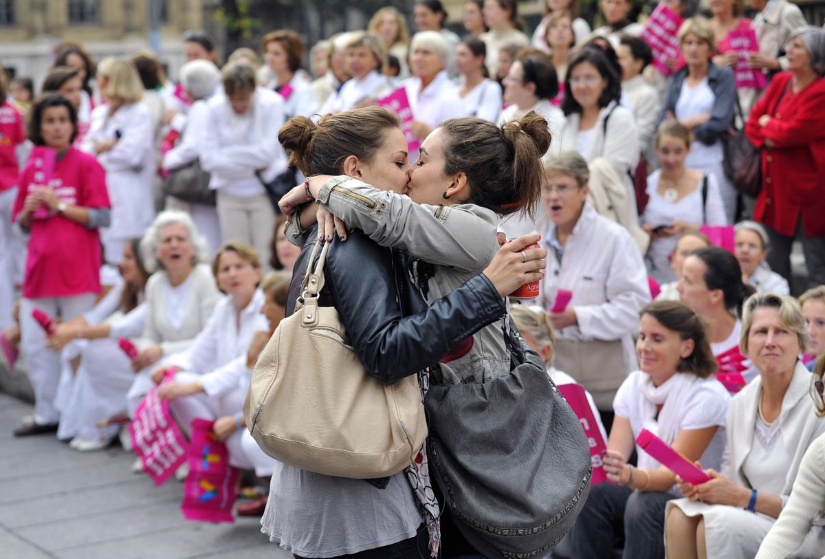 tonguedepressors:  A lesbian couple kiss in front of people taking part in a demonstration