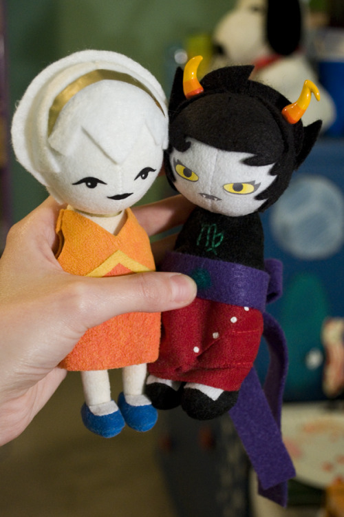 [Description: Someone holding up a pair of sprite-form Rose Lalonde and Kanaya Maryam plush dolls th
