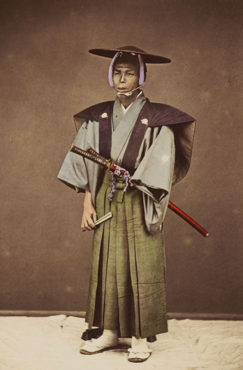 Studio photo of Samurai, in formal dress, holding fan.  Circa 1876, by photographer  Kozaburo Tamamu