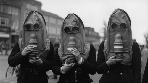 Air raid wardens demo a trio of spooky elephantine gas masks, designed for the elderly, during a sim