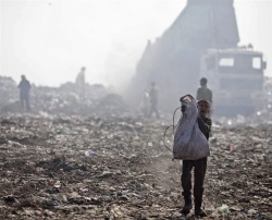 fotojournalismus:  A young Palestinian boy carries a bag with scavenged plastic on a dump site outside Gaza City on Nov. 8, 2012. The site is just a few hundred meters away from the Israeli border and the workers have to be careful not to come too close