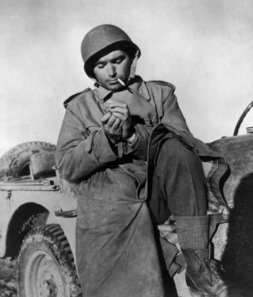 Robert Capa, pauses for a smoke while on assignment in Tunisia as a combat photographer and correspondent for LIFE Magaz