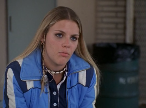 Kim, rocking a braid, with her signature cowry-shell choker and blue puffy jacket.