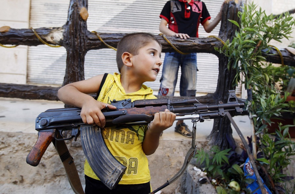 drugwar:  A boy plays with an AK-47 rifle owned by his father in Azaz. 