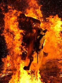 Men ride their horses through flames during