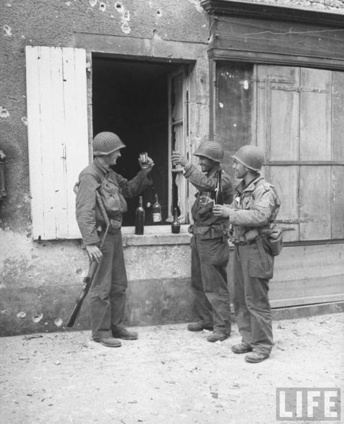 gunsandposes:France 1944: On the second day of the Normandy invasion, American soldiers toast each o