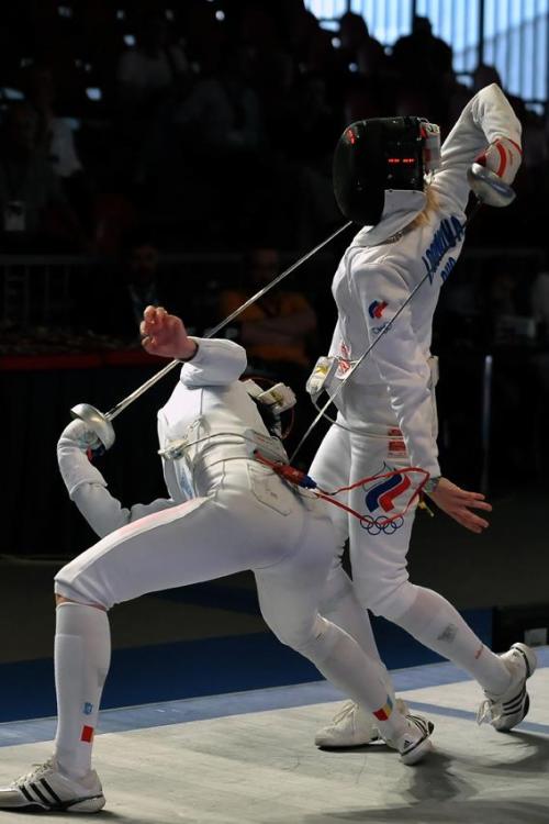 aeide-thea: modernfencing: [ID: two epee fencers in a bout. The one on the left is twisted over and 