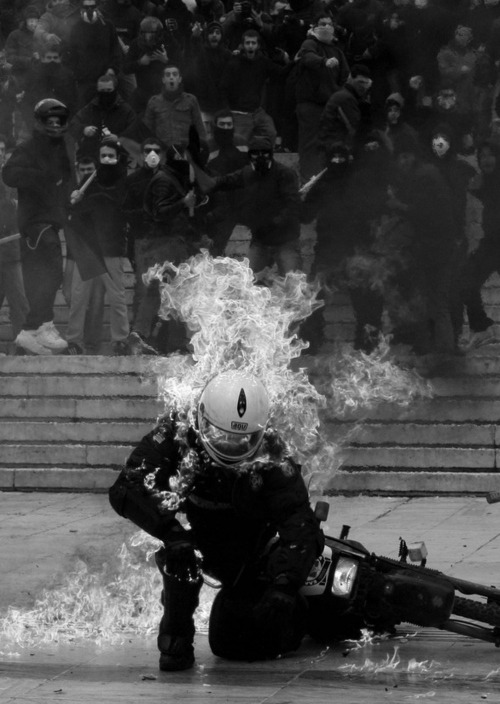 kremmling-orgulho:  A police officer is hit by a petrol bomb as police in full riot gear clash with protesters in front of parliament in on February 23,2011 in Athens, Greece.