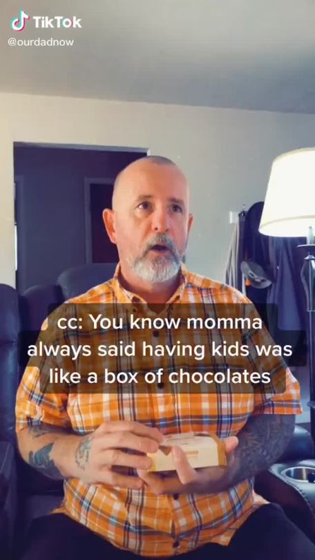 pan-positivity:[Video description: a man holding a small chocolate box is wearing a orange plaid shirt, he is mostly bald but has a beard and small amount of hair on his head. The man also has tattoos on his arms.  Man: you know, momma always said having